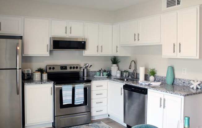 kitchen with white cabinets, granite countertops, and stainless steel appliances and built-in microwave  at Huntsville Landing Apartments, Huntsville, AL