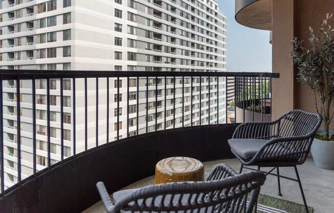 a balcony with two chairs and a table and a building in the background
