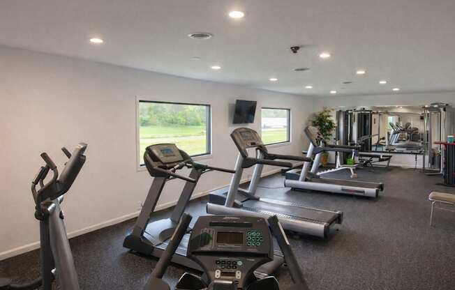 A gym with treadmills, elliptical machines, and other exercise equipment.