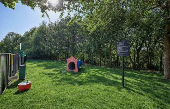 A dog park with a sign and a red and blue dog house.