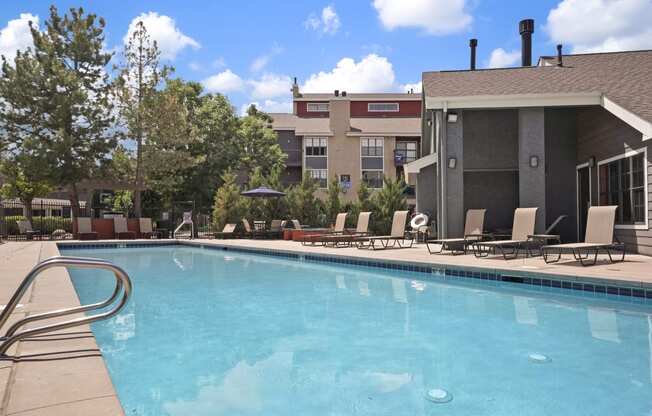 a swimming pool with chairs and a building in the background