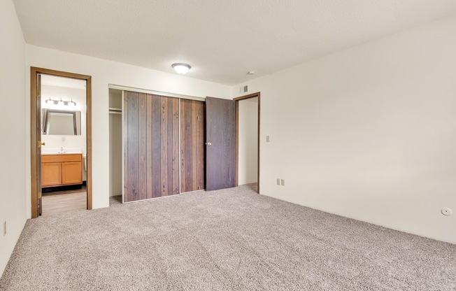 A room with a grey carpet and a wooden cabinet.
