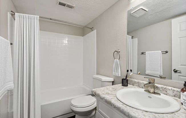 Model Bathroom with White Cabinets and Wood-Style Flooring at Broadmoor Village Apartments in Salt Lake City, UT.