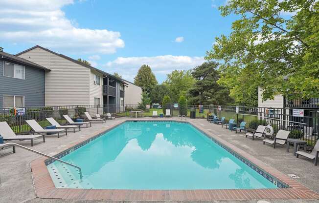 A swimming pool surrounded by lounge chairs and trees.