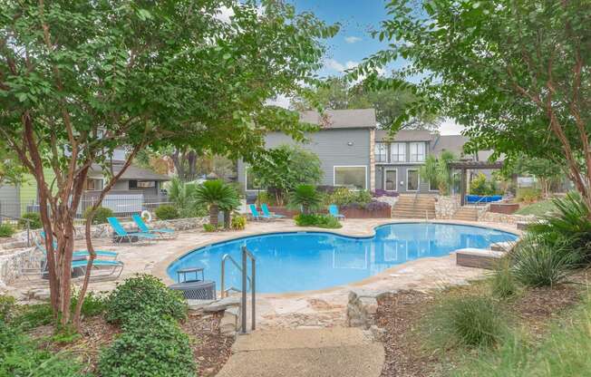 a swimming pool with trees and chairs around it