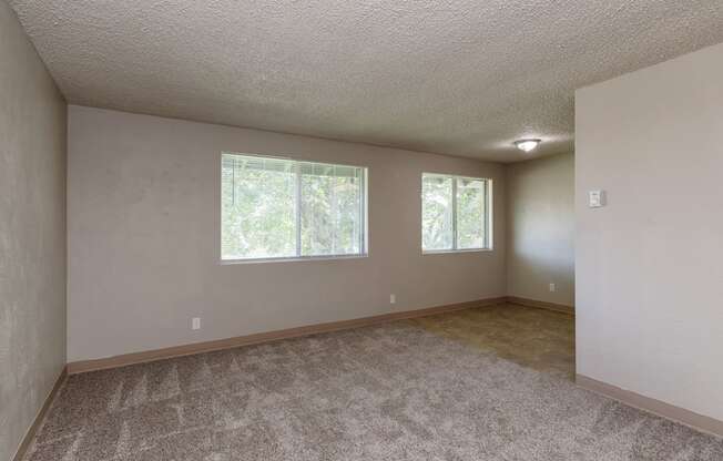 A room with a carpeted floor and two windows.