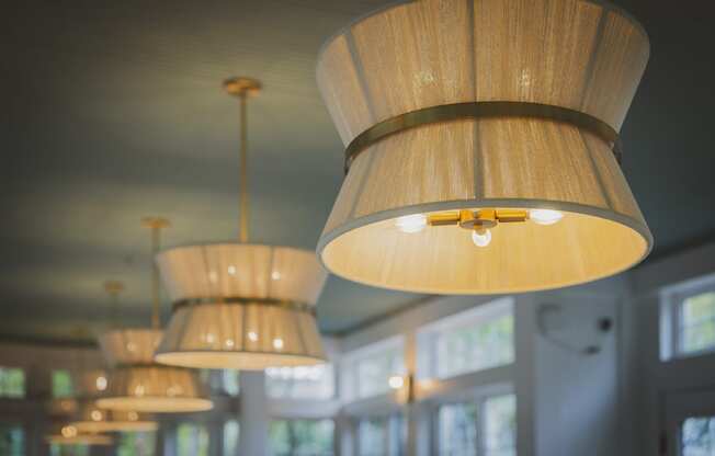 a row of hanging wooden lamps in a room with windows