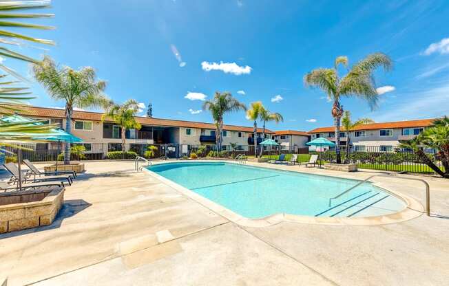 a swimming pool with palm trees and a building in the background