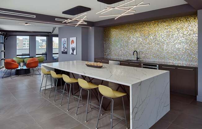 A modern kitchen with a long white island and yellow chairs.