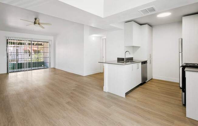 A kitchen with white cabinets and a wooden floor.