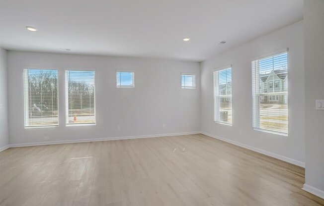 A large empty room with wooden floors and windows.
