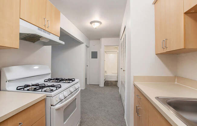A kitchen with a white stove and wooden cabinets at Brookside Apartments, Springfield