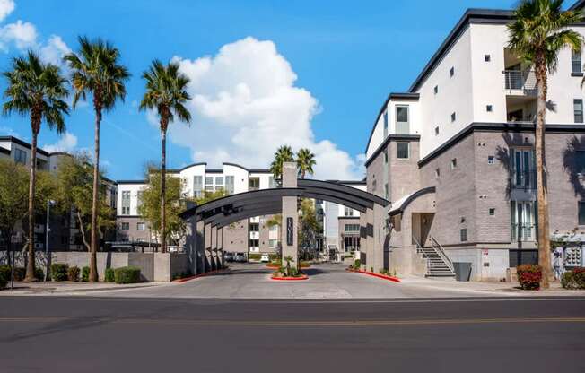 A modern building with a curved entrance and palm trees in front.