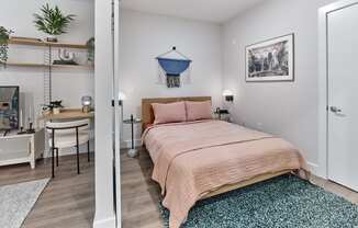 Chic bedroom area in a studio apartment at The Mint Rahway, featuring a comfortable bed, workspace, and stylish decor.