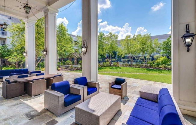 a patio with blue couches and chairs and a view of a garden