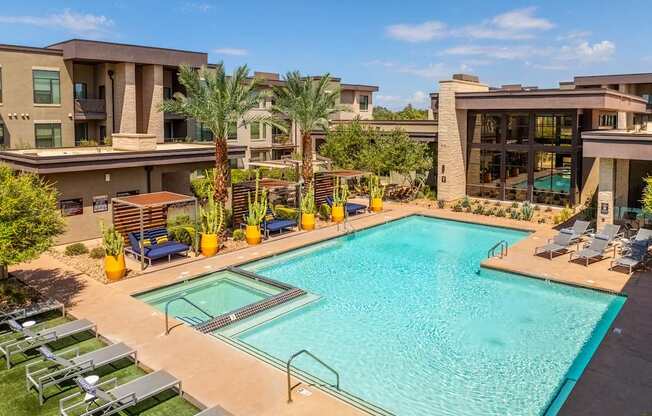 A large swimming pool surrounded by lounge chairs and palm trees.