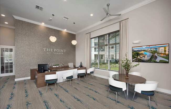 A conference room with a long table and chairs, a television, and a large window with blinds.