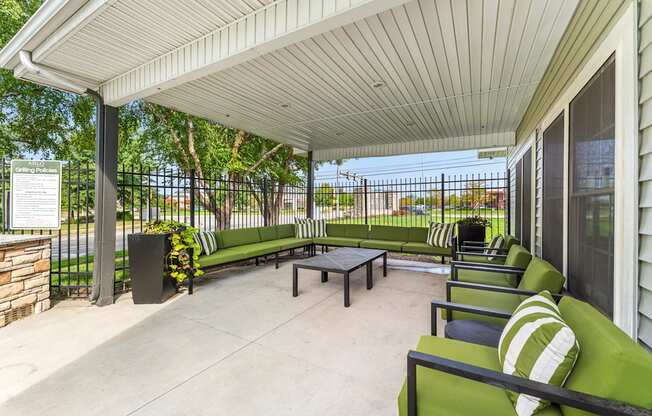 A patio with a white roof and green couches.