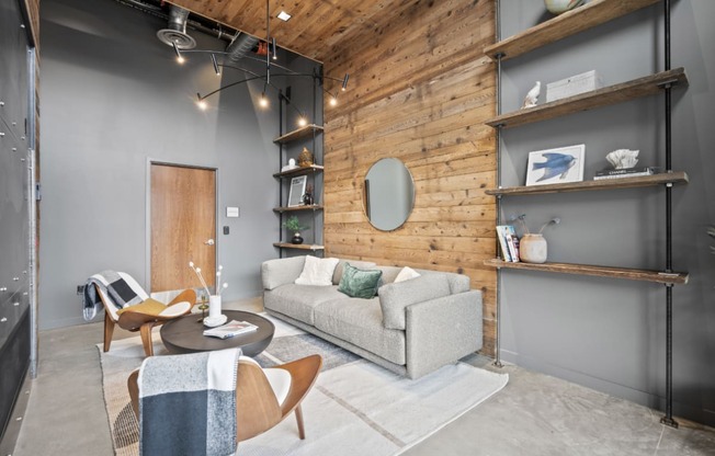 a living room with a gray couch and a wooden wall