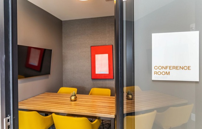 A conference room with a wooden table and yellow chairs.