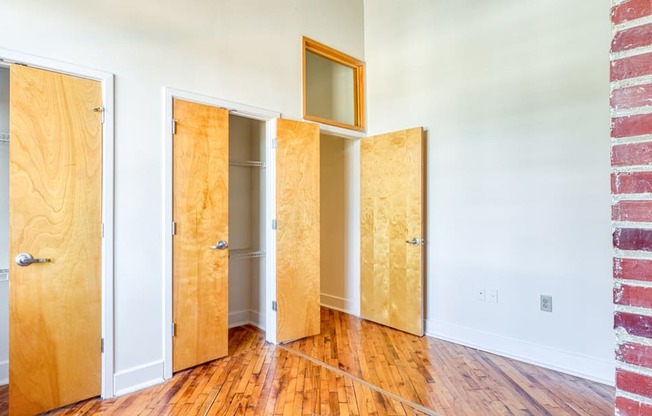 a row of doors in a room with wood floors and a brick wall