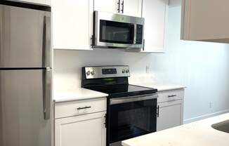 a kitchen with white cabinets and a stove and a microwave