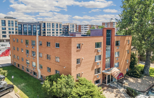 Charming brick apartment building in a vibrant urban neighborhood with modern architecture and lush greenery.