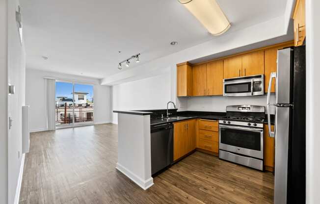 a kitchen with black counter tops and stainless steel appliances and wood floors