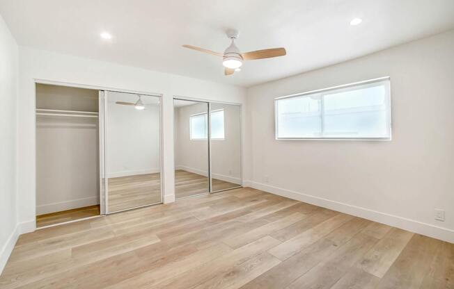 A room with a ceiling fan and sliding doors.