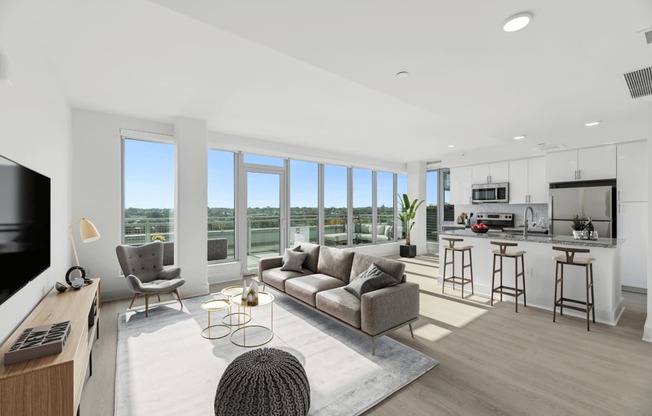 an open living room with a couch and a chair and a kitchen with a counter