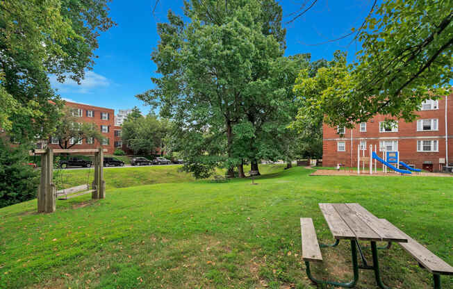 a park with a picnic table and a playground in front of a building