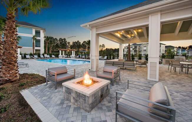 A patio with a fire pit and chairs.