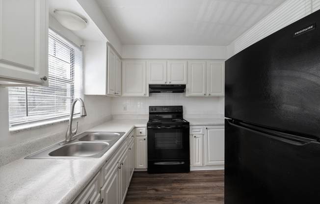 Modern kitchen with sleek black appliances, polished countertops, and bright cabinetry offering ample storage and charm.