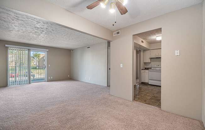 Omaha, NE Evergreen Terrace Apartments. A living room with a ceiling fan and a kitchen in the background