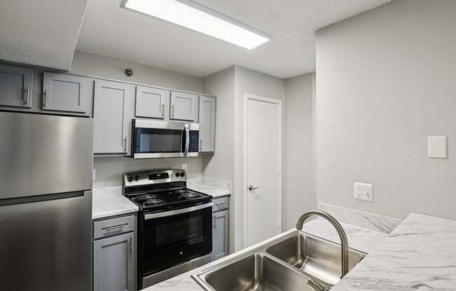 A kitchen with a stainless steel refrigerator, microwave, oven, and sink.