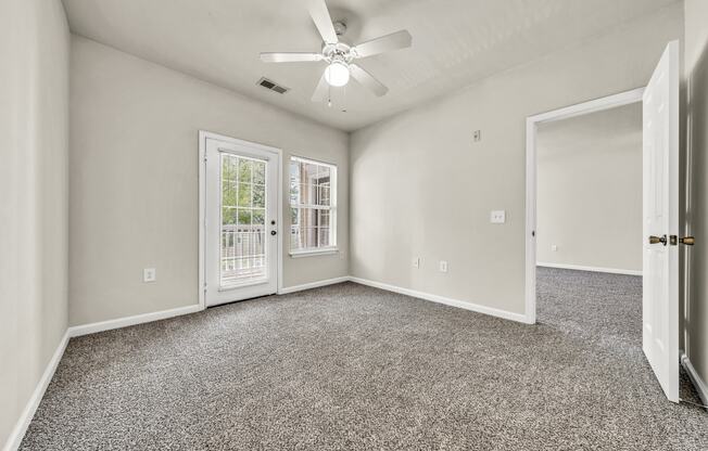 an empty room with carpet and a ceiling fan