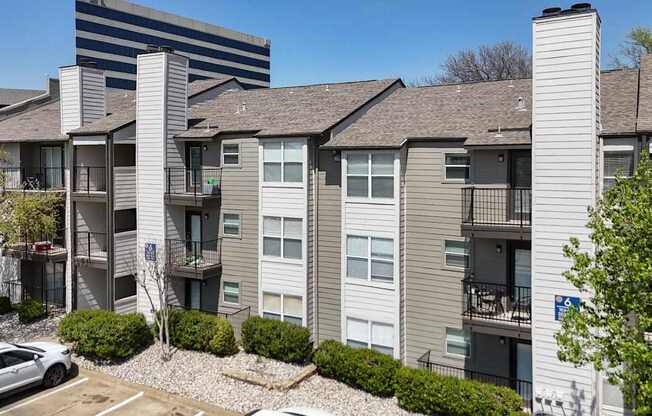 An apartment building with gray and white walls and balconies at The Park on Preston Apartments in Dallas, TX
