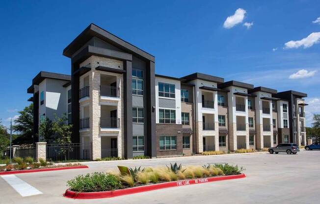 a row of apartment buildings with a parking lot at Hunters Creek Apartments, Denton, TX 76210