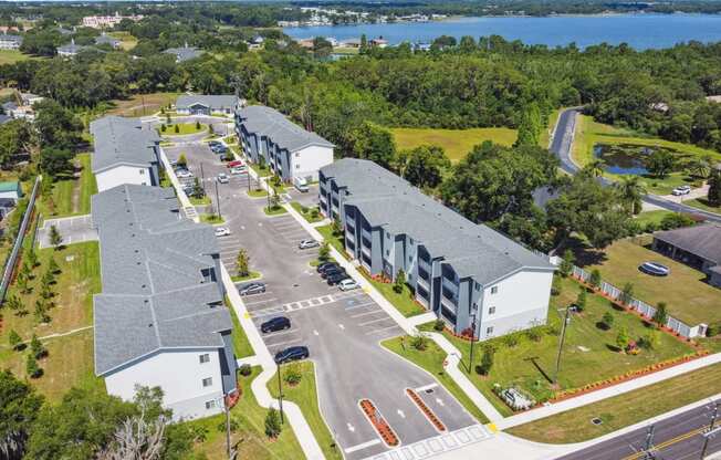 an aerial view of apartment buildings with a lake in the background at Gibson Oaks, Lakeland, 33809