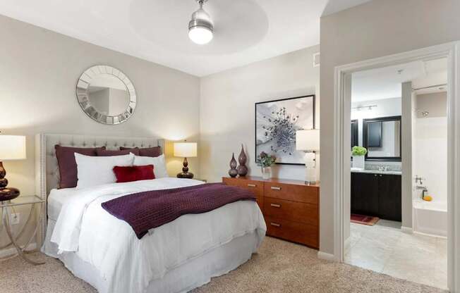 A bedroom with a white bed and a round mirror on the wall.