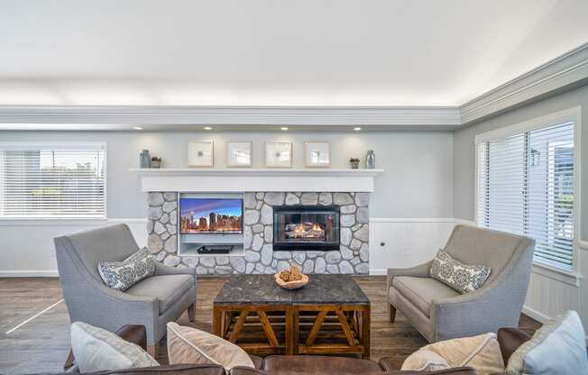 a living room with a stone fireplace and chairs and a table