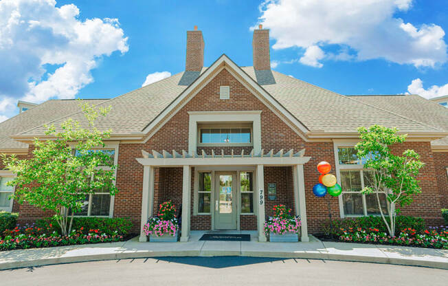 the front of a brick house with balloons on the side
