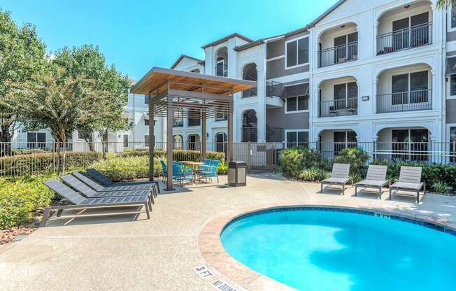 A pool area with a sun lounger and a table.