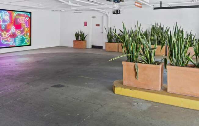 a room with plants in pots on the floor and a painting on the wall