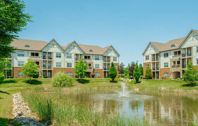 a pond with a fountain in front of an apartment building