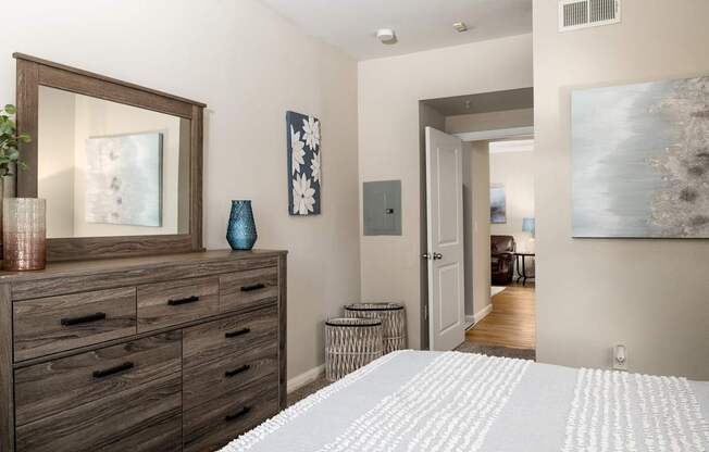 A bedroom with a large bed and a dresser with a mirror above it.