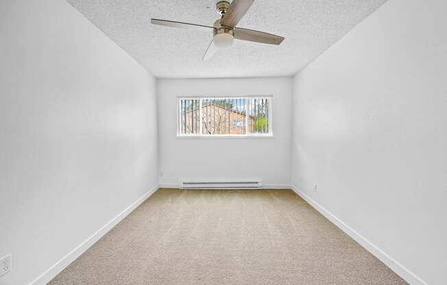 an empty room with a ceiling fan and a window