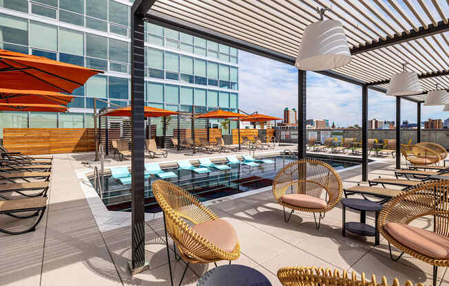 A rooftop patio with a pool and chairs.