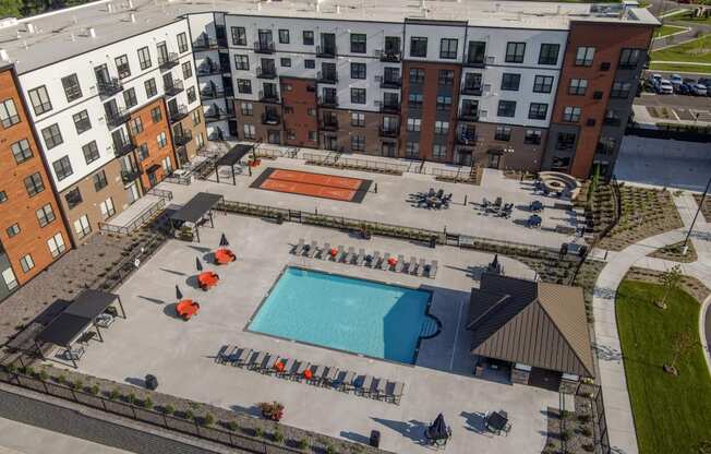 An aerial view of a pool surrounded by chairs and umbrellas in a courtyard.