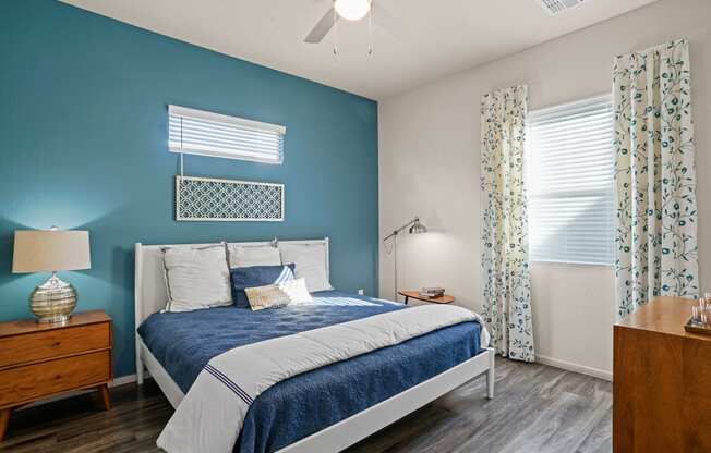 a blue and white bedroom with a bed and a ceiling fan